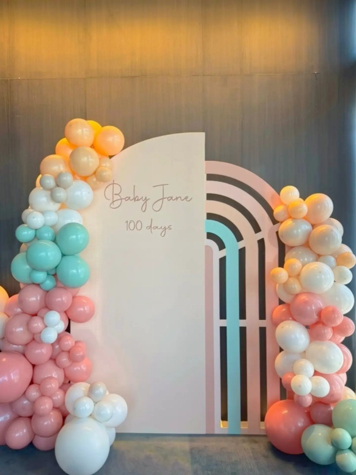 Celebratory backdrop with pastel balloons and a sign for Baby Jane's 100 days.