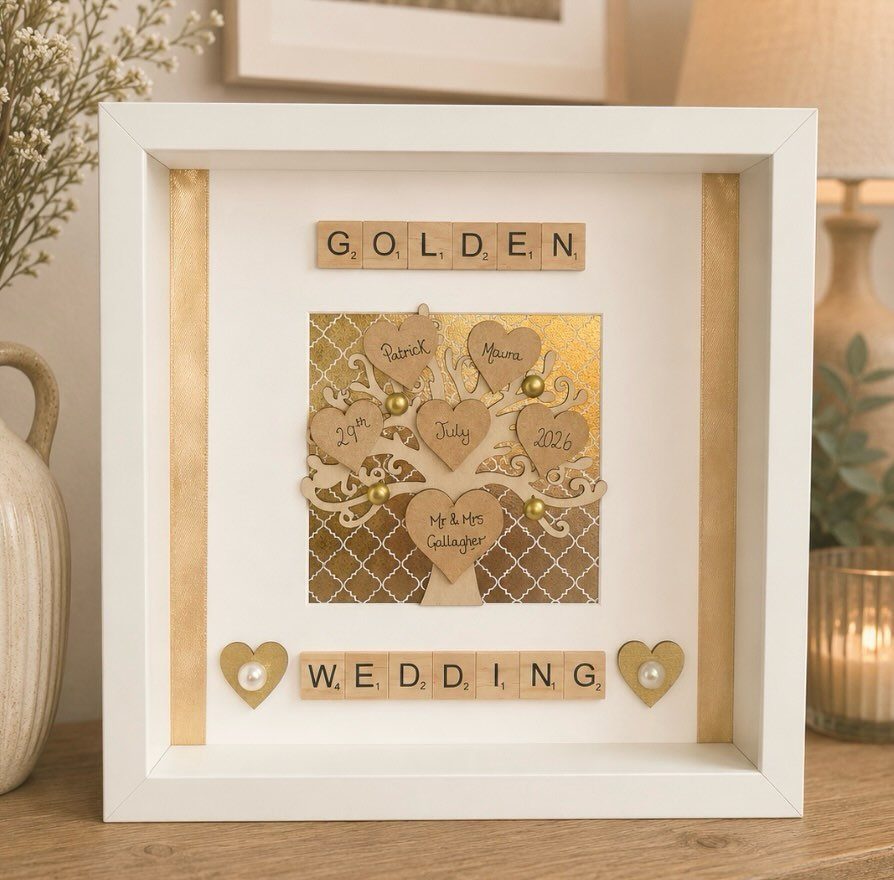 White shadow box frame with a wooden tree and golden wedding lettering.