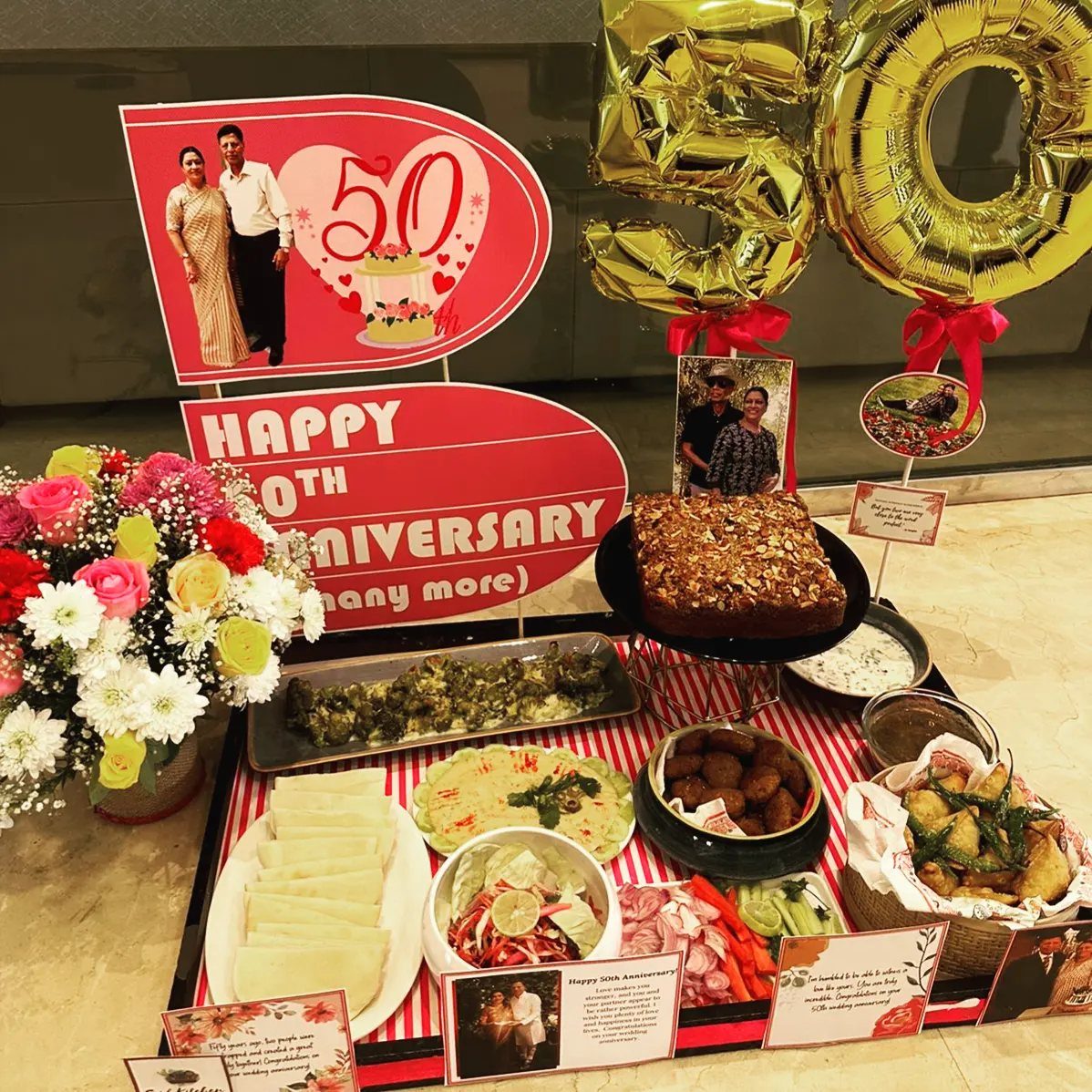 Celebratory table with gold 50 balloons, food, flowers, and anniversary photos.