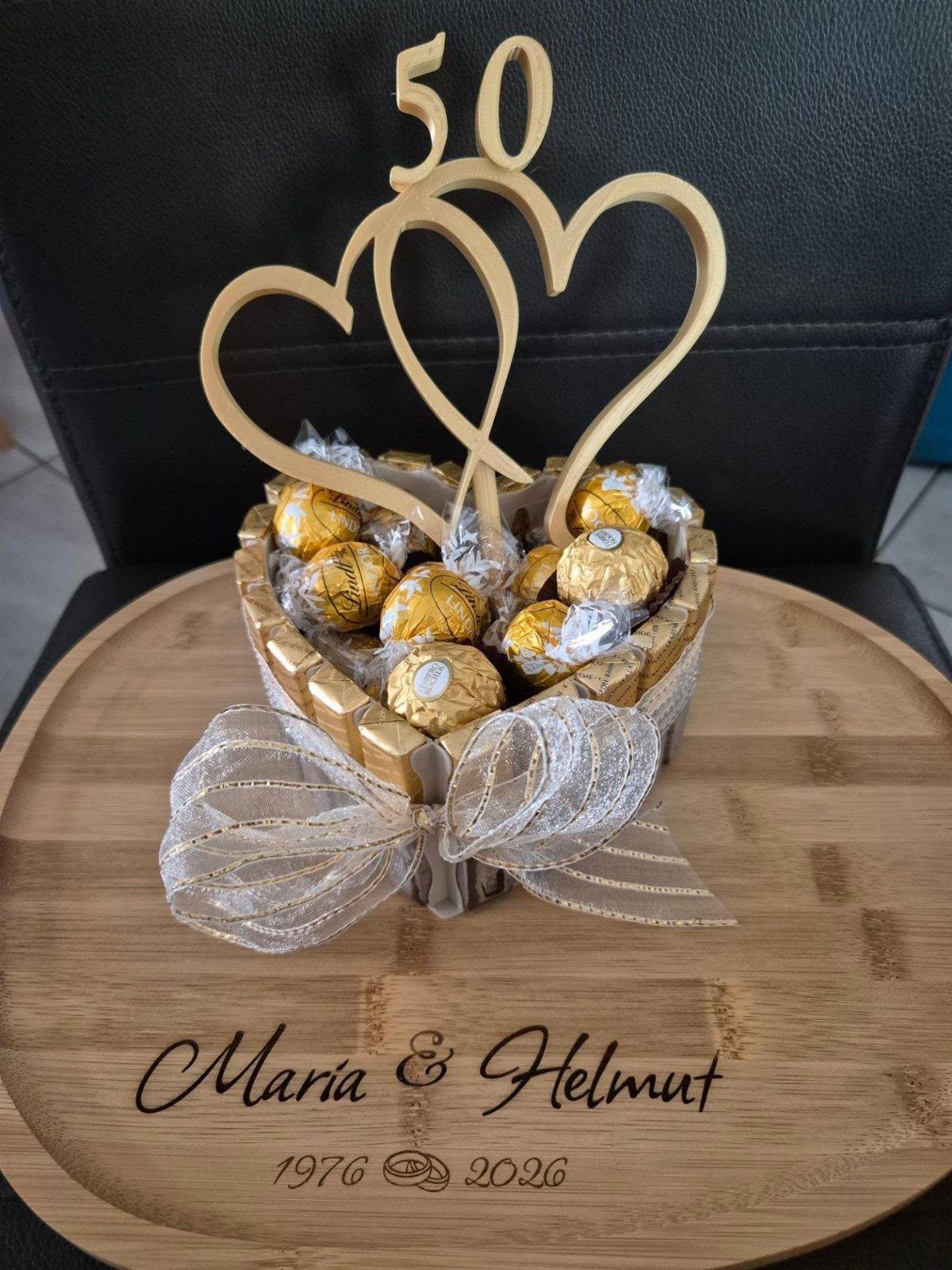 Heart-shaped chocolate basket with gold 50 topper on an engraved wooden board