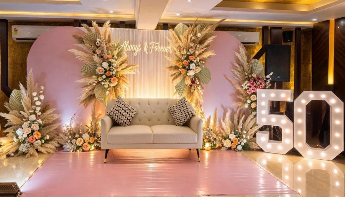 Celebratory anniversary setup with a beige loveseat, floral arrangements, and glowing 50 numbers.