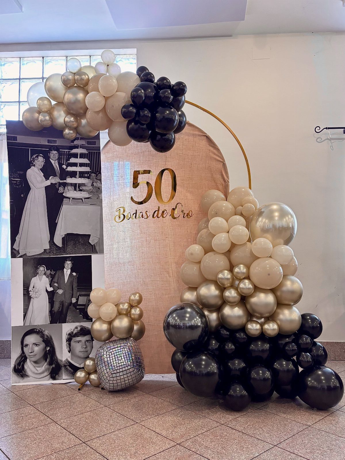 Gold and black balloon decorations with vintage wedding photos for a 50th anniversary.