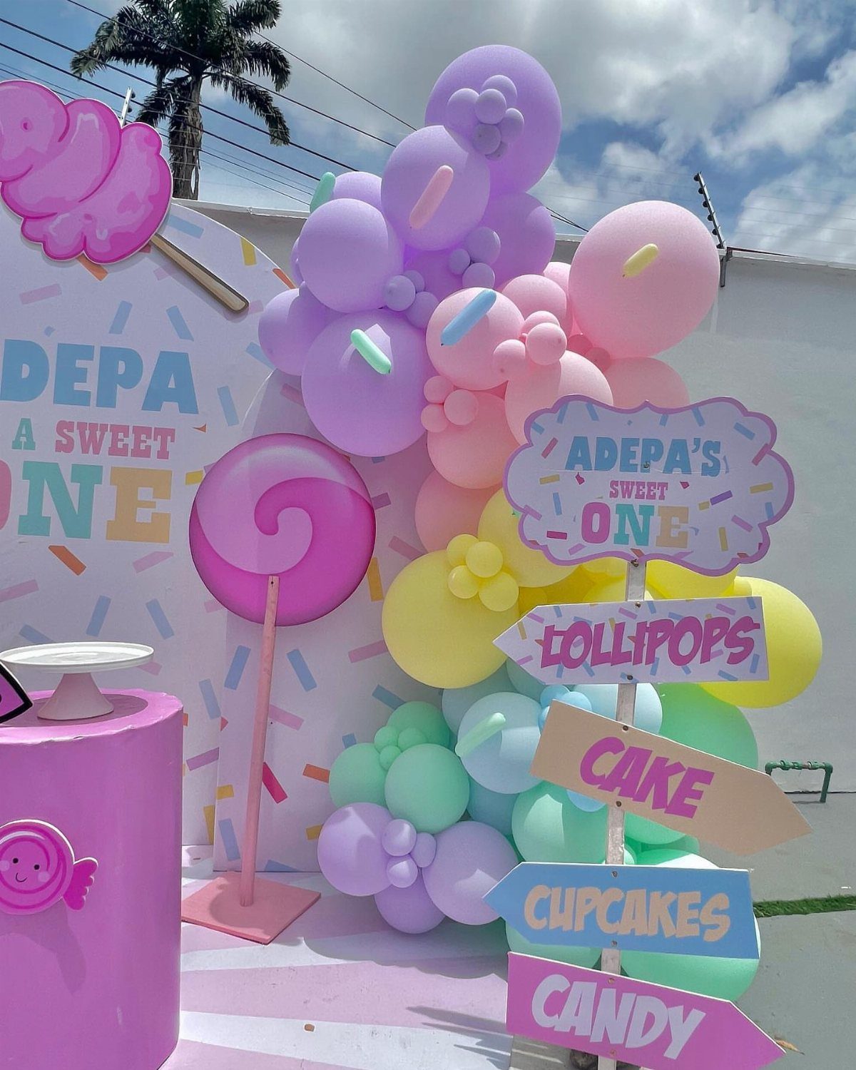 Colorful candy themed party decorations with pastel balloons and large lollipop props.