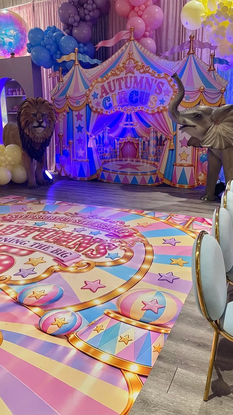 Circus party setup with a carnival tent backdrop, animal figures, and colorful balloons.