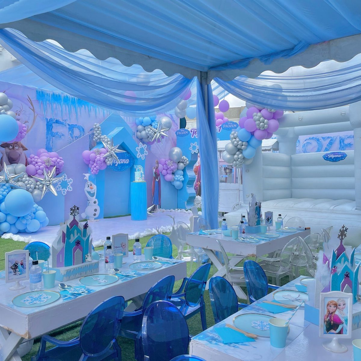 Frozen themed party setup with blue decorations, balloons, and movie character figures.