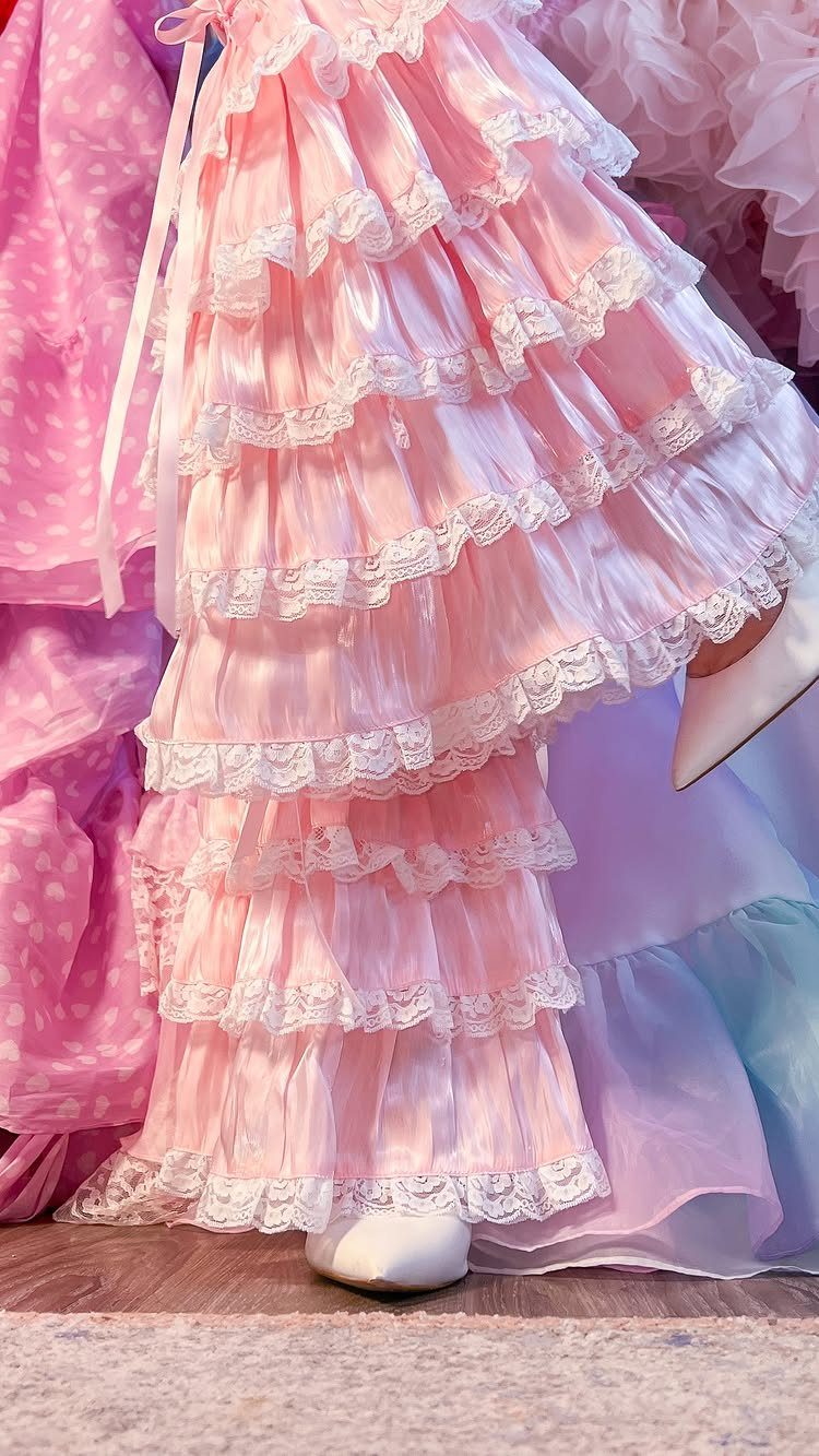Tiered pink satin dress with multiple layers of white lace ruffles on mannequin