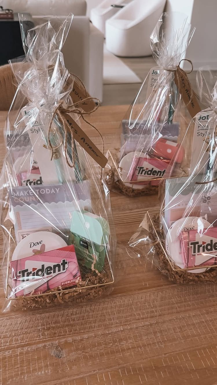 Clear cellophane gift bags filled with gum, chocolate, and small toiletries on wood.