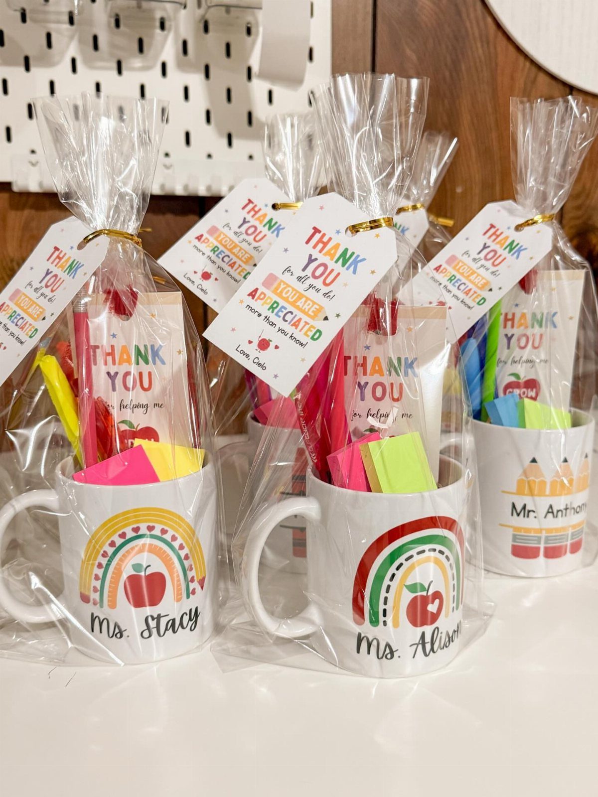 White mugs filled with stationery and thank you cards wrapped in cellophane bags.