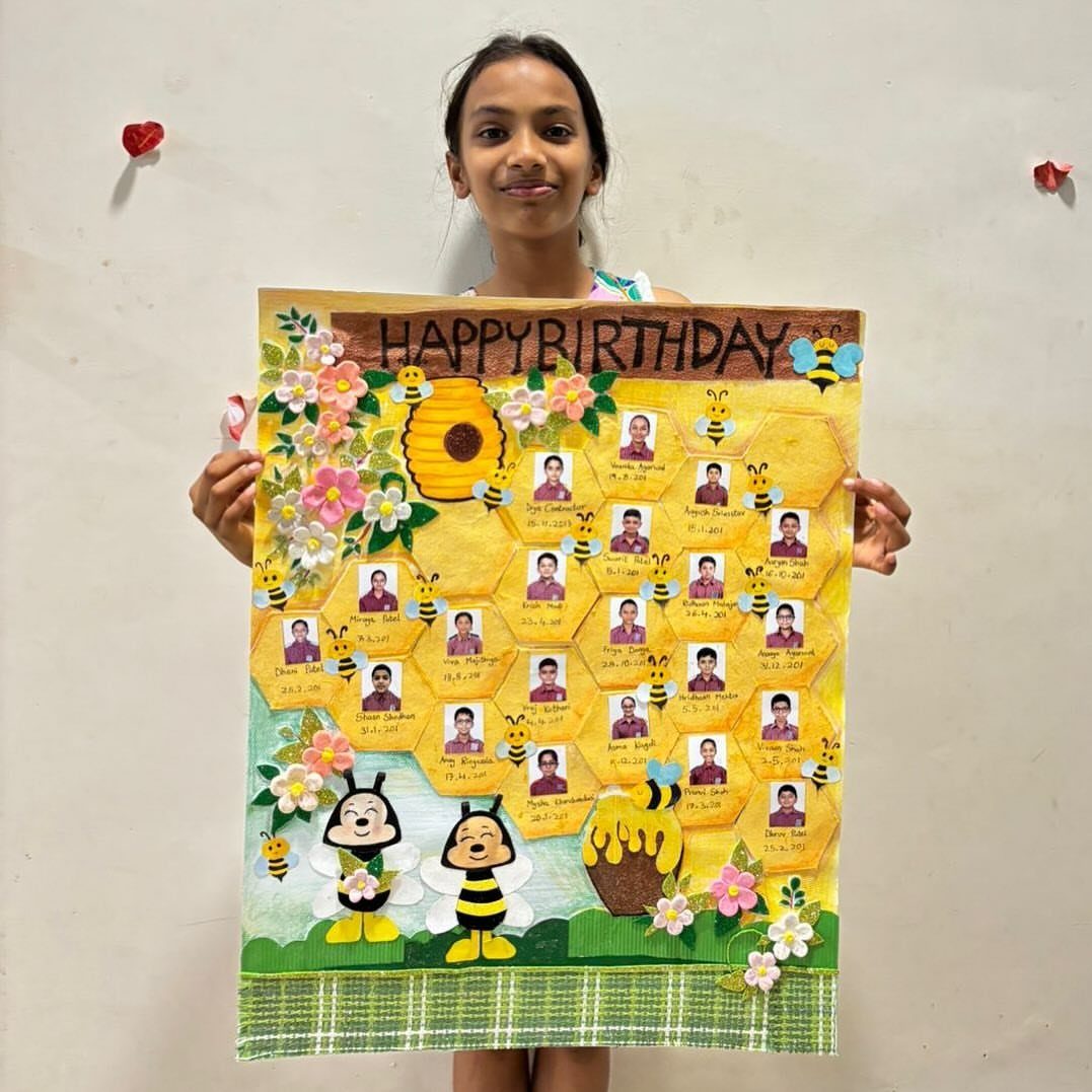 Girl holding a honeycomb birthday board featuring student photos and bee decorations.