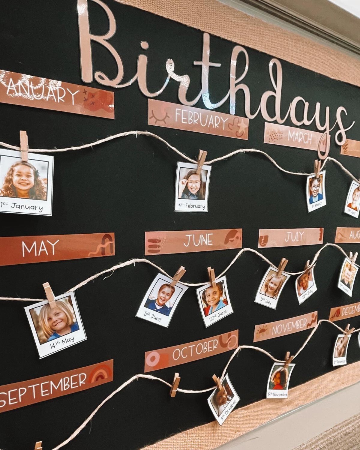 Birthday bulletin board with student photos clipped to twine under monthly labels.