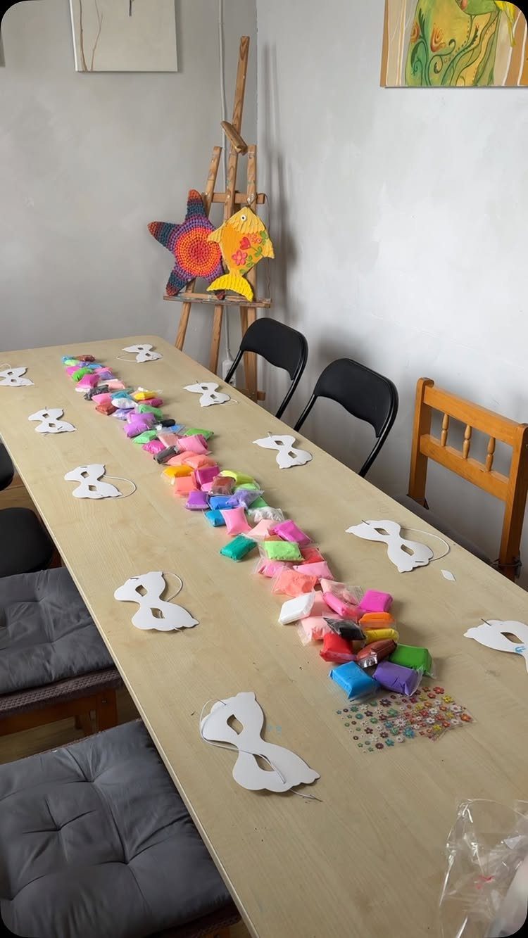 White paper mask cutouts and colorful fabric pouches arranged on a wooden table.