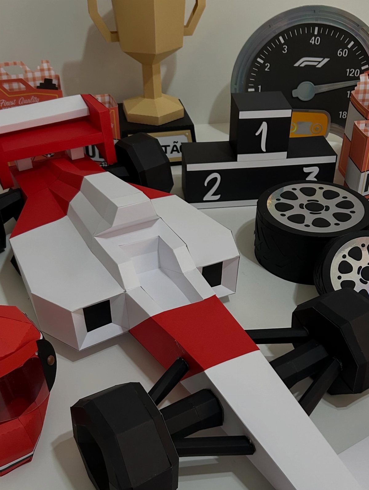 Papercraft Formula 1 race car with a matching trophy and podium on white surface