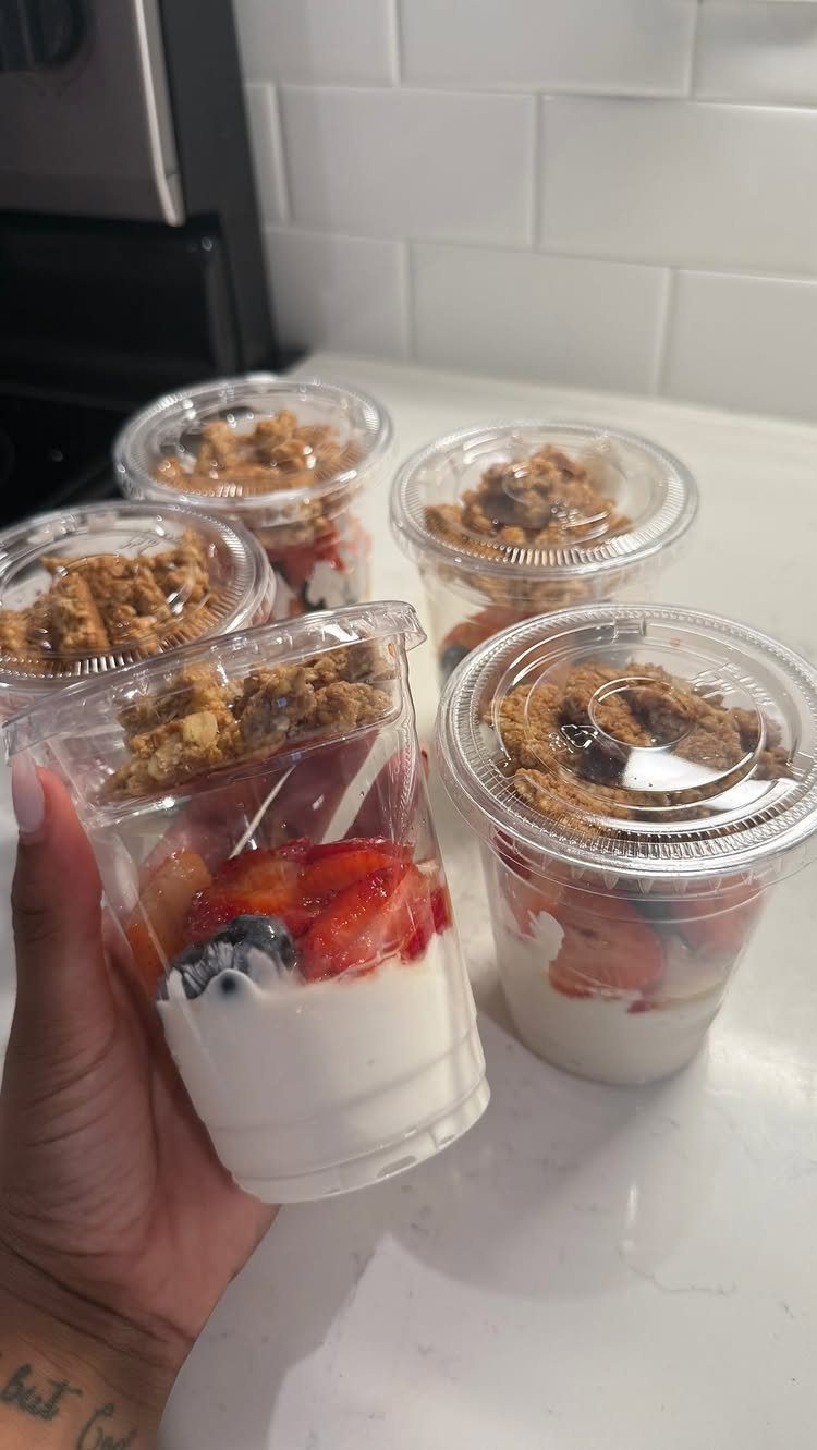 Fruit and yogurt parfaits with granola in clear plastic cups on a counter