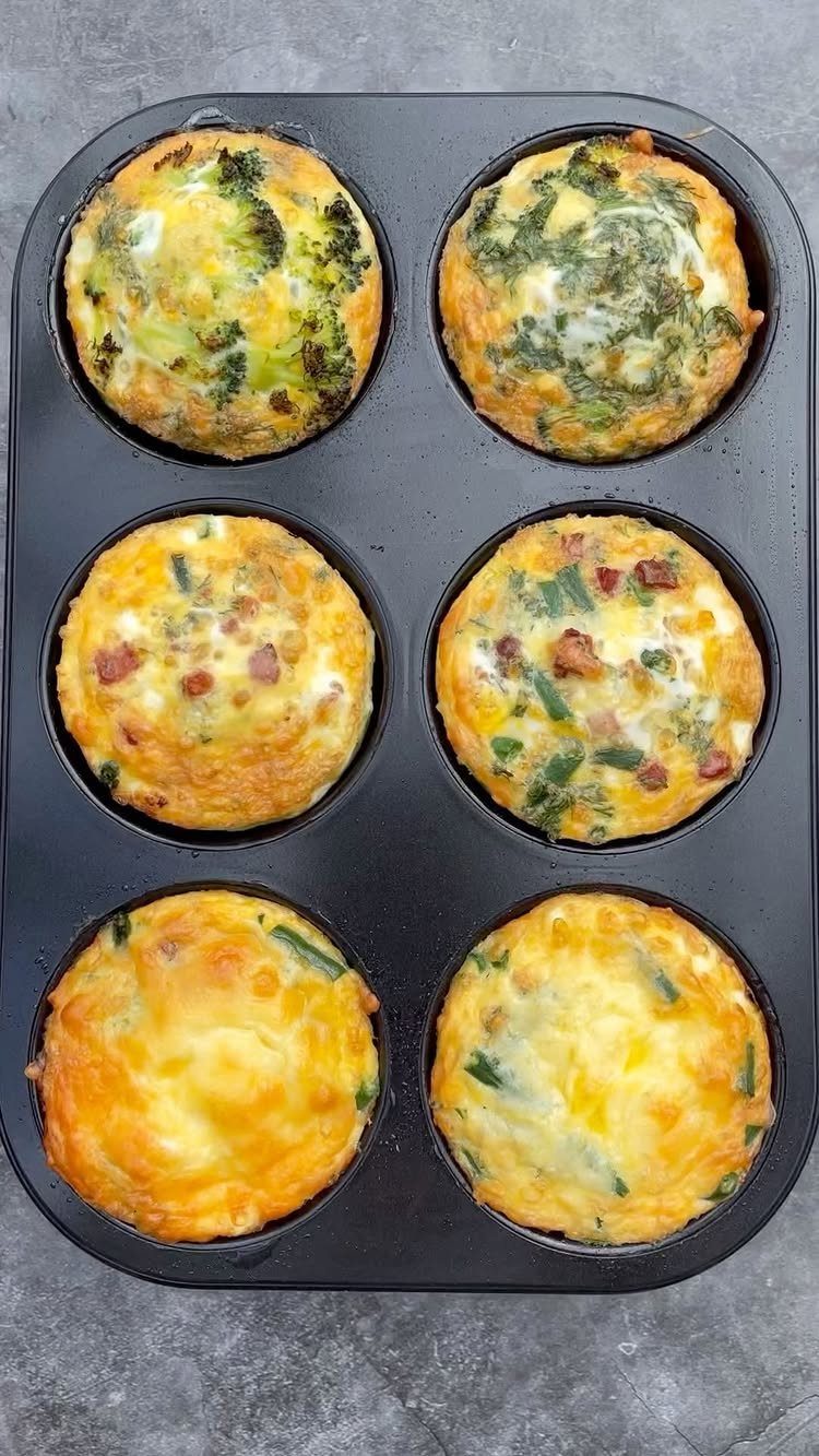 Six mini frittatas with vegetables and bacon in a black muffin tin.