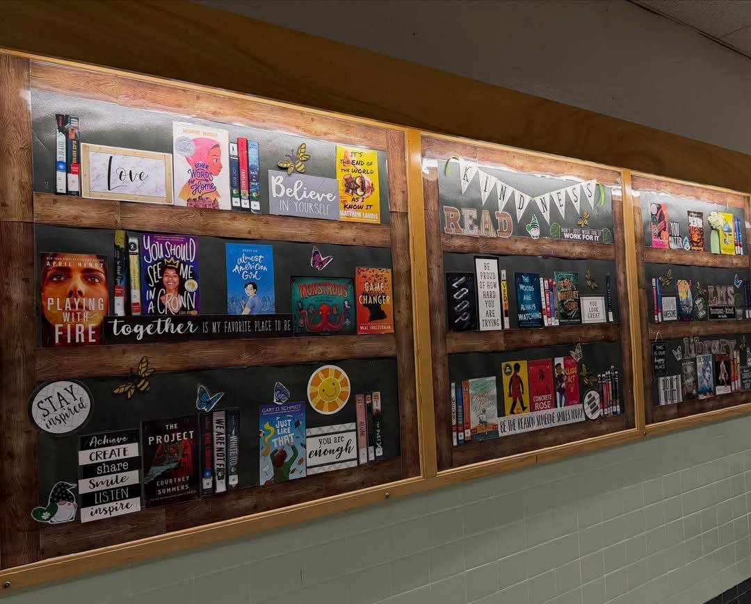 Bookshelf-themed bulletin boards featuring printed book covers and motivational quotes on a wall.