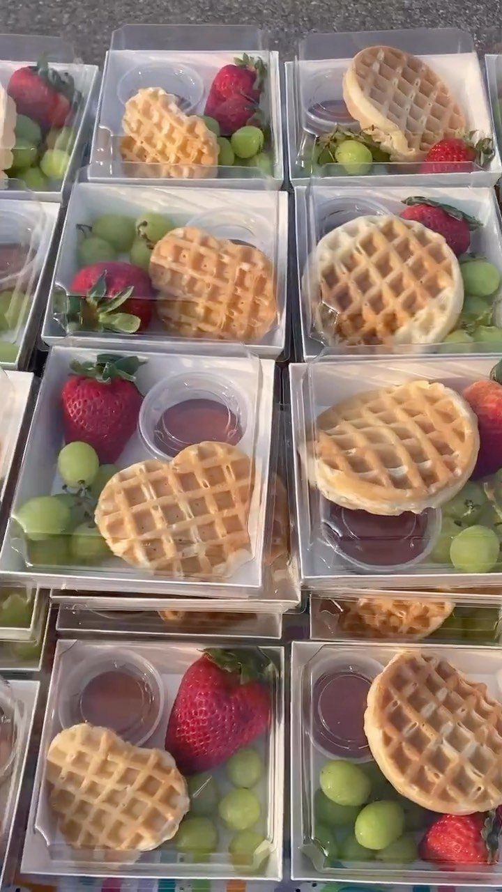 Heart-shaped waffles with strawberries and grapes in individual clear plastic containers.