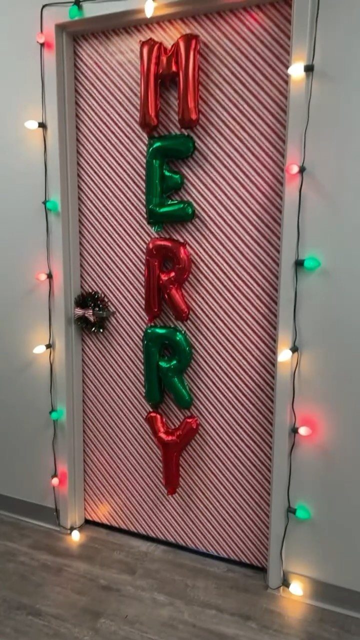 Door decorated with red and white stripes, MERRY balloons, and colorful string lights.
