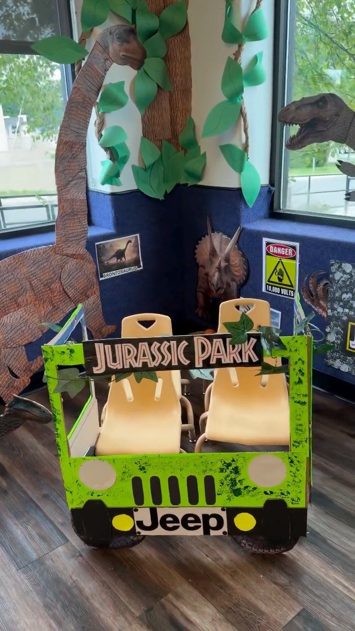 Dinosaur themed classroom corner with a cardboard Jeep and prehistoric creature decorations.