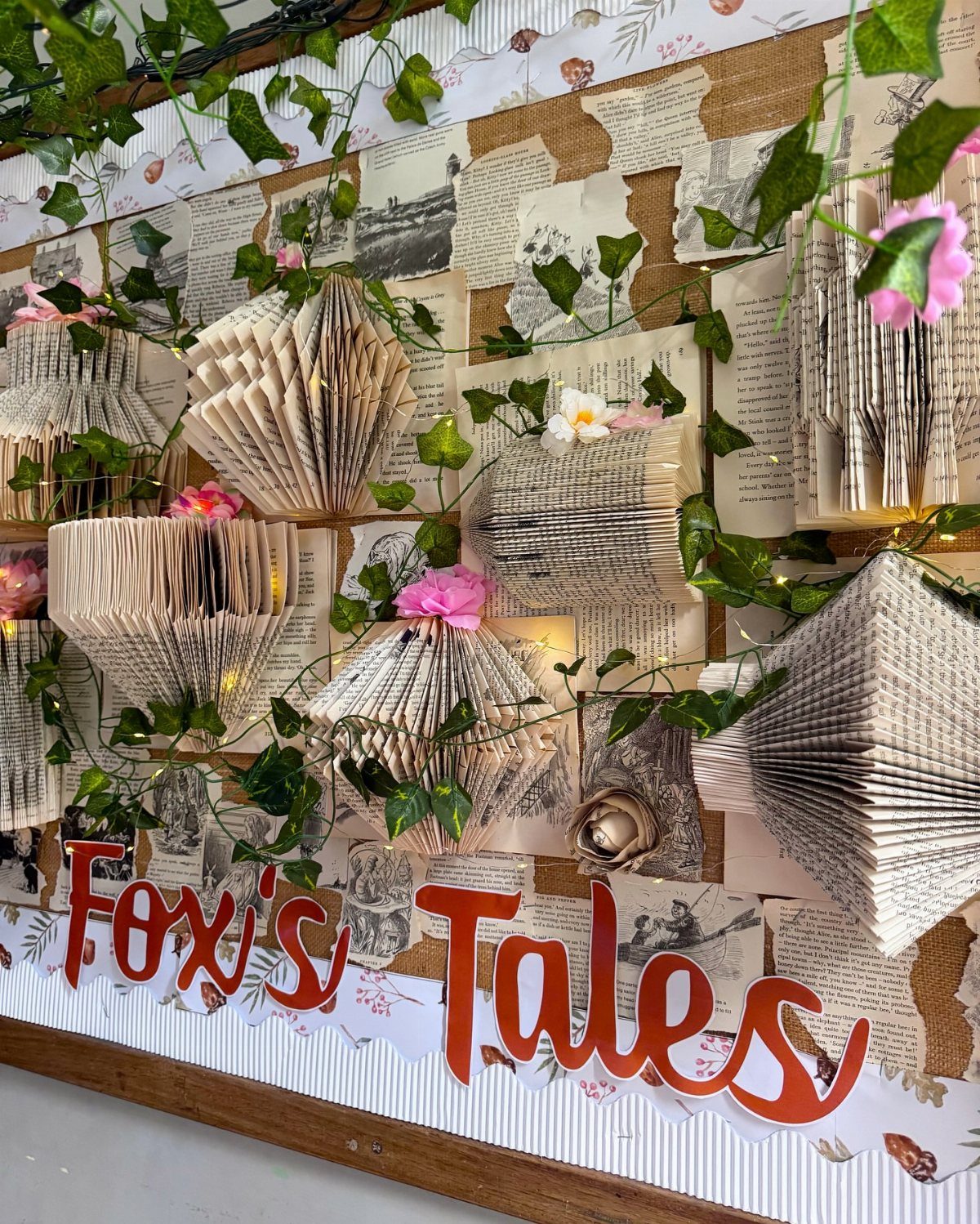 Folded open books and green ivy vines on a vintage paper wall backdrop.