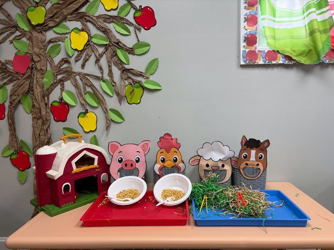 Farm animal themed classroom activity with a toy barn and animal feeding stations.