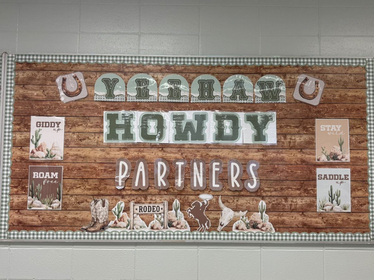 Western themed bulletin board with wood background, cowboy boots, and Howdy text.