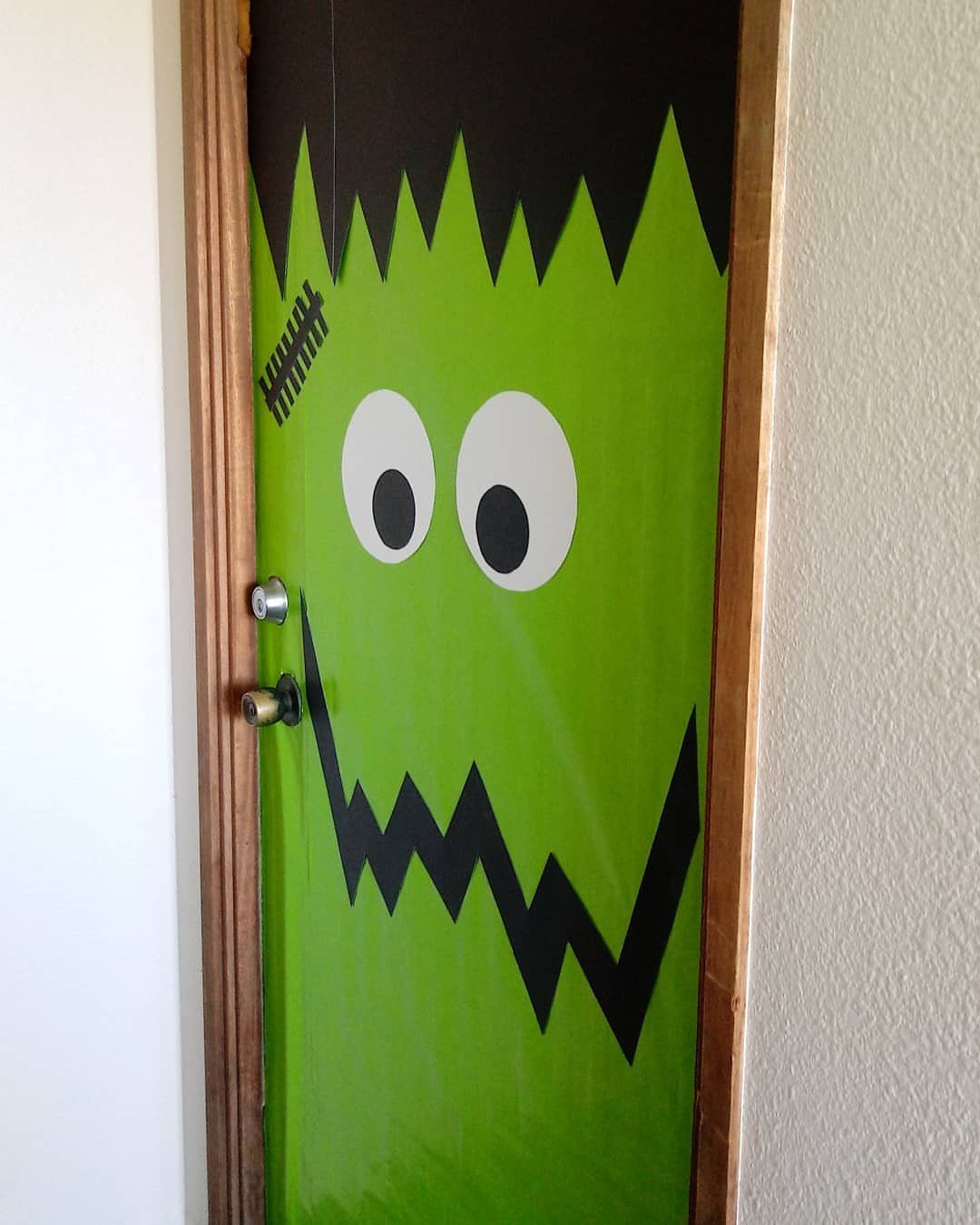 Green Frankenstein monster face decoration on a classroom door with black jagged hair.