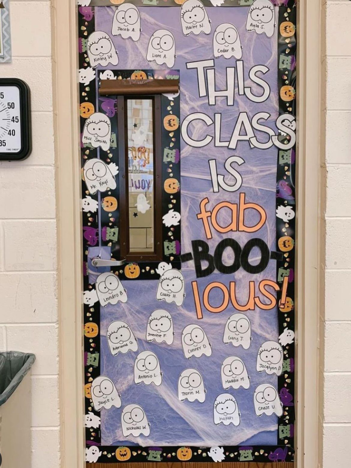 Classroom door decorated with purple paper, ghost cutouts, and fab-BOO-lous text.