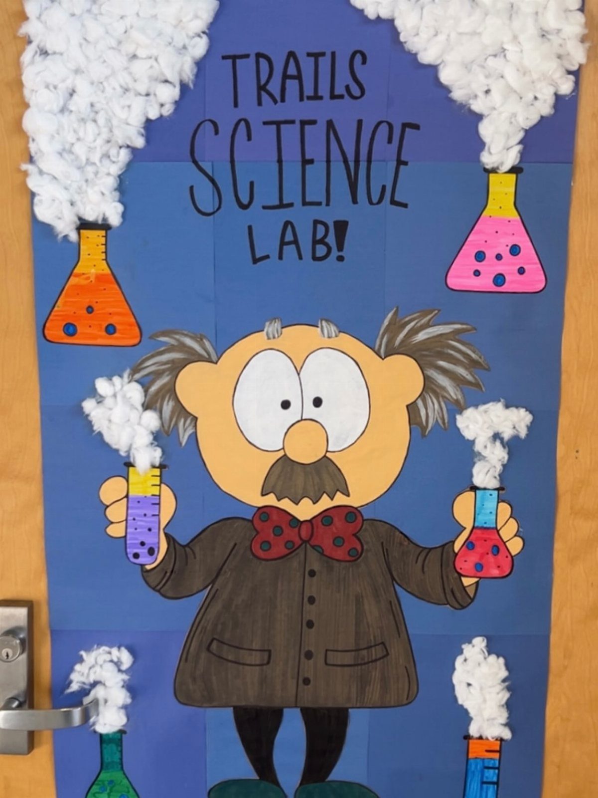 Mad scientist classroom door decoration with colorful bubbling flasks and cotton smoke clouds.