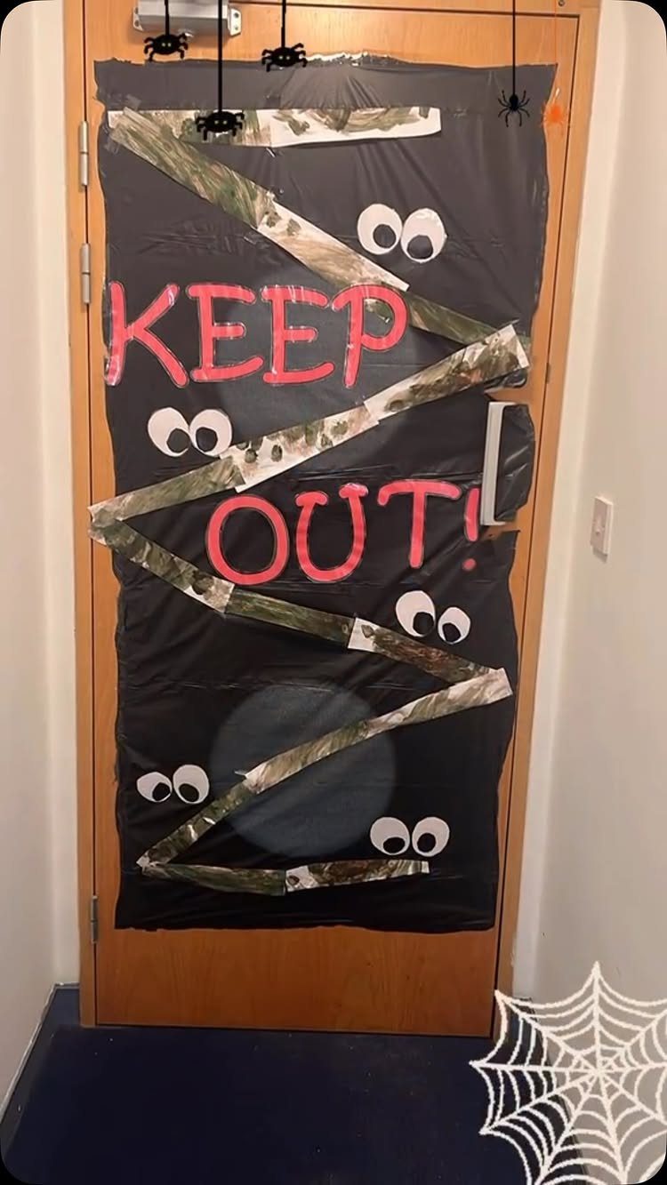 Halloween classroom door decorated with black plastic, googly eyes, and red Keep Out text.