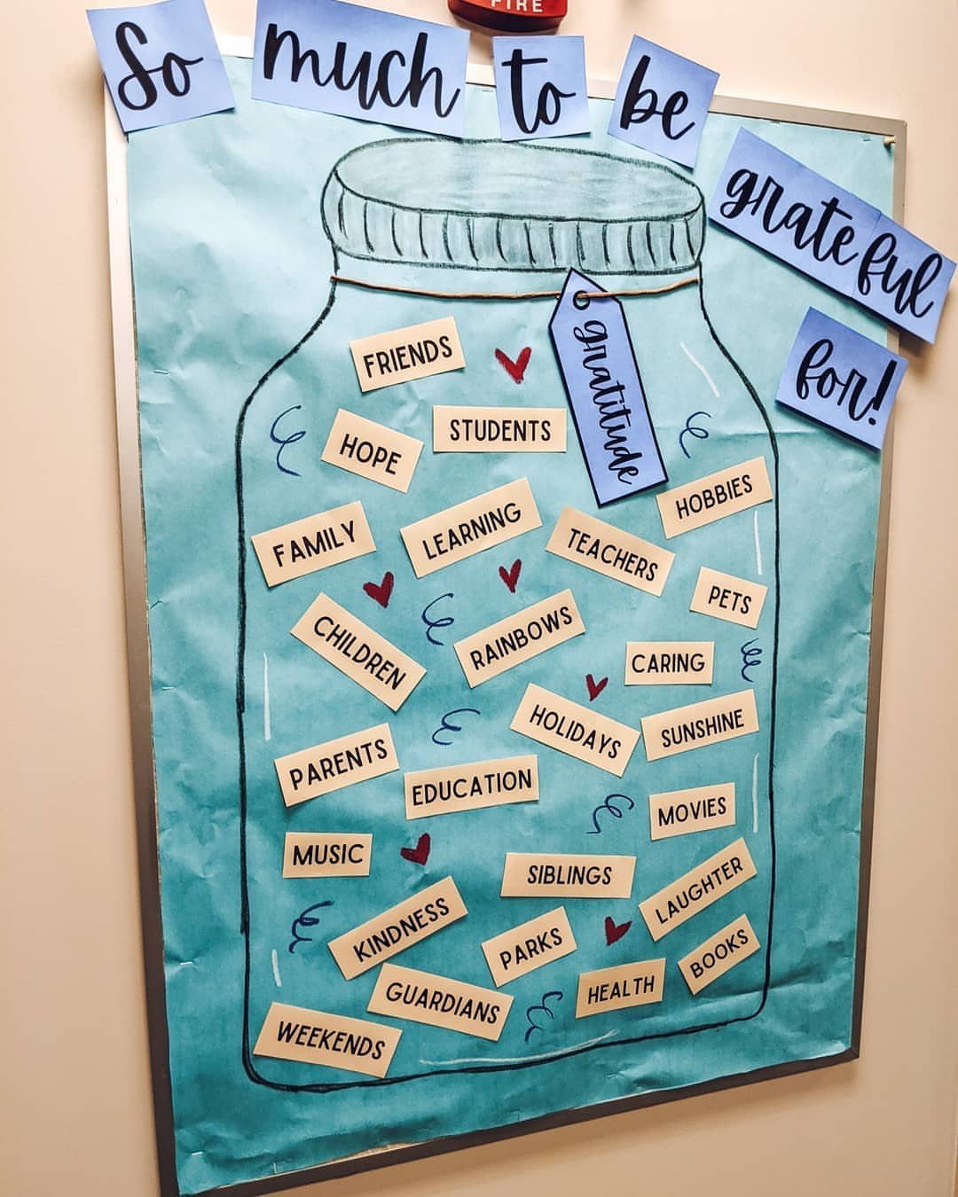 Gratitude jar bulletin board with slips of paper listing things to be thankful for.
