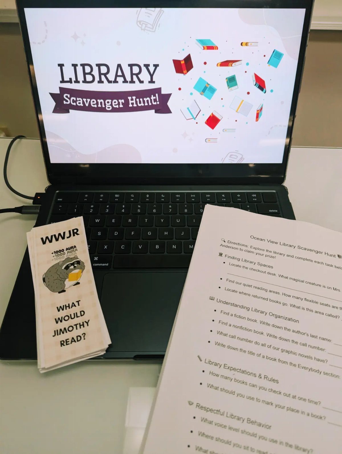 Laptop screen and printed checklist for a library scavenger hunt on a desk