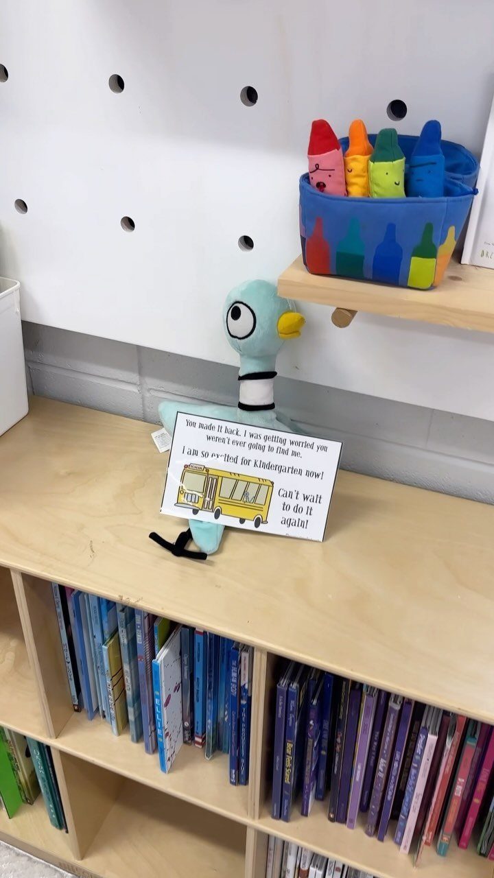 Blue plush bird and a school bus note on a classroom bookshelf