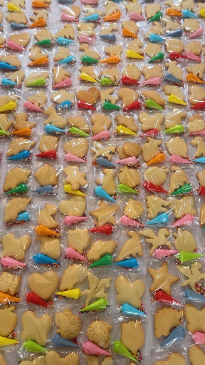 Individual cookie decorating kits in plastic bags with colorful icing piping bags.
