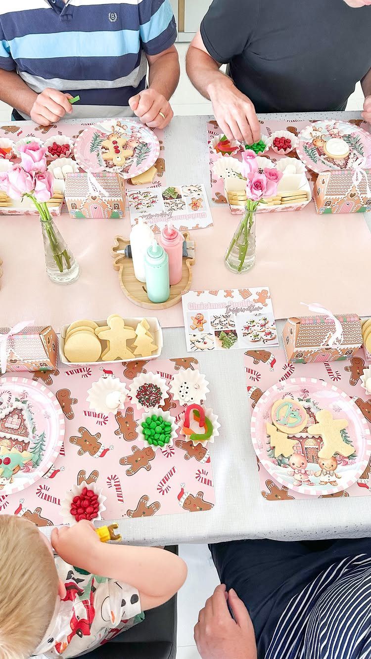 People decorating gingerbread man cookies at a table with colorful frosting and sprinkles.
