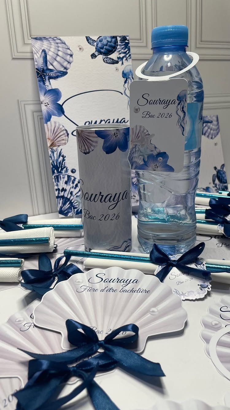 Personalized blue and white party favors with custom labels on water bottles and tumblers.