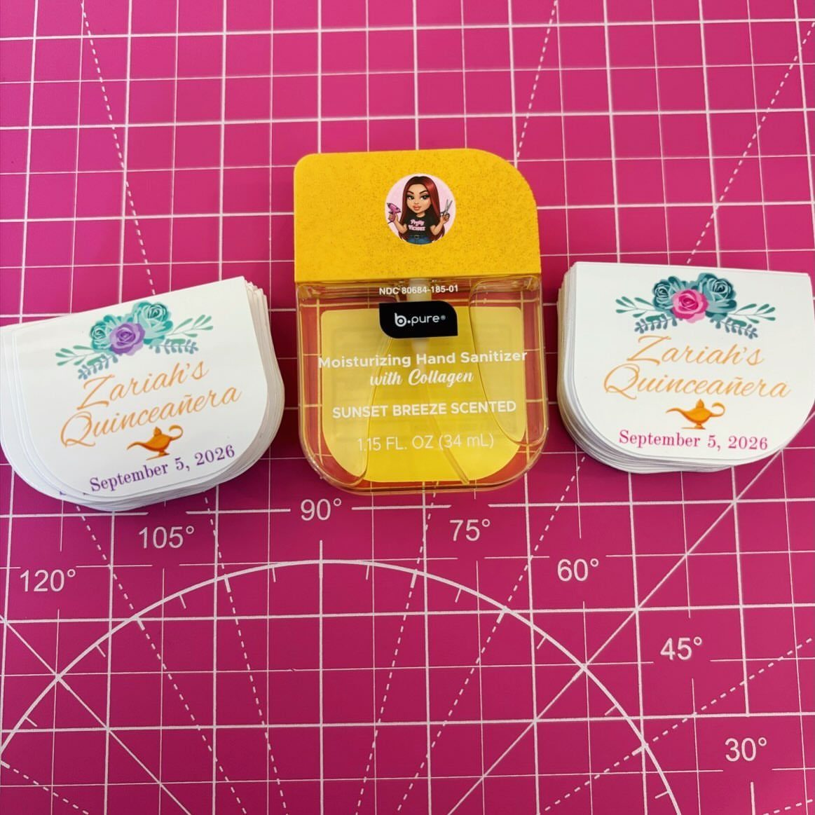 Hand sanitizer bottle and custom labels for a Quinceañera on a pink mat.