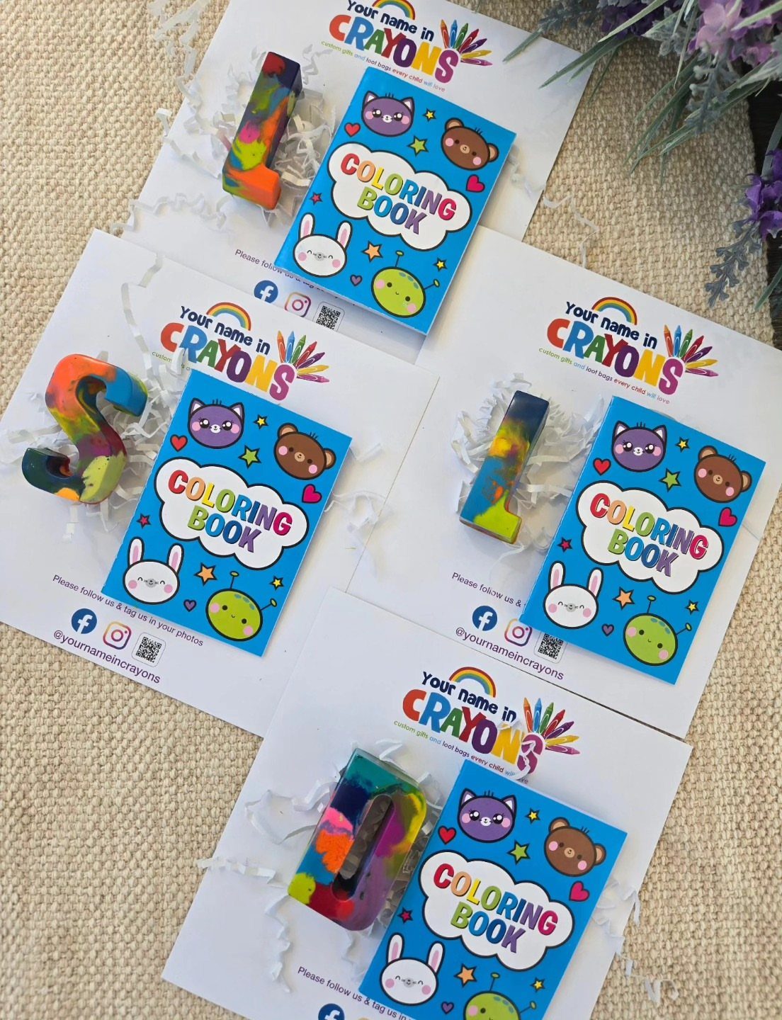 Colorful initial-shaped crayons and small coloring books arranged on white gift cards.