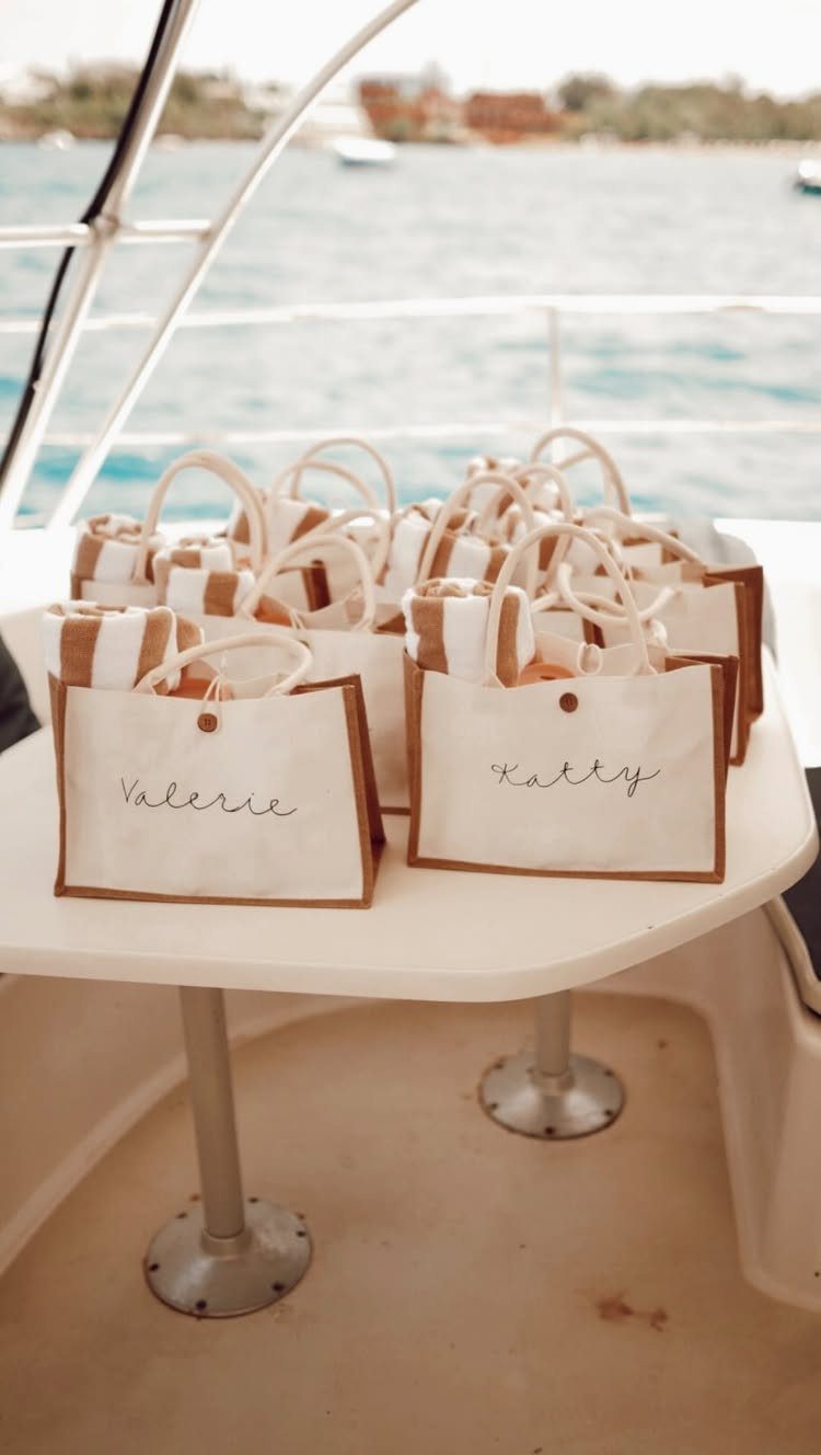 Small white personalized canvas tote bags with names on a boat table.