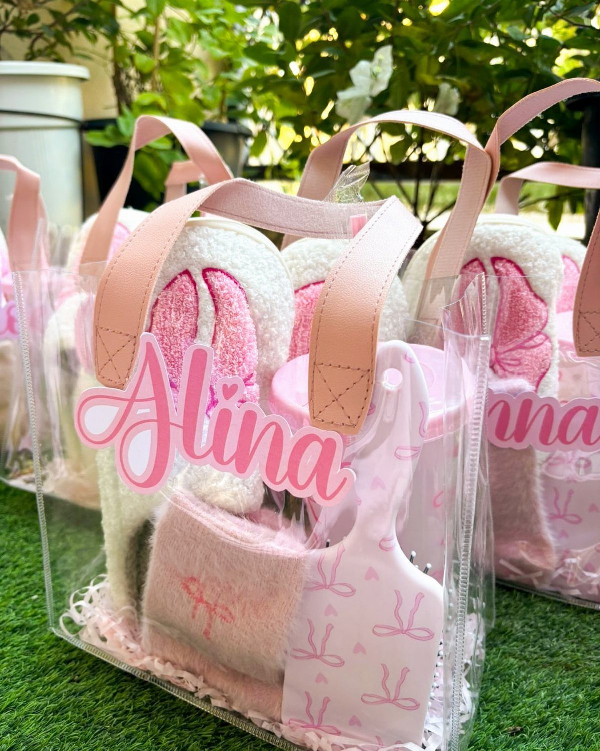 Clear gift bags filled with pink fluffy slippers and accessories for a sleepover party.