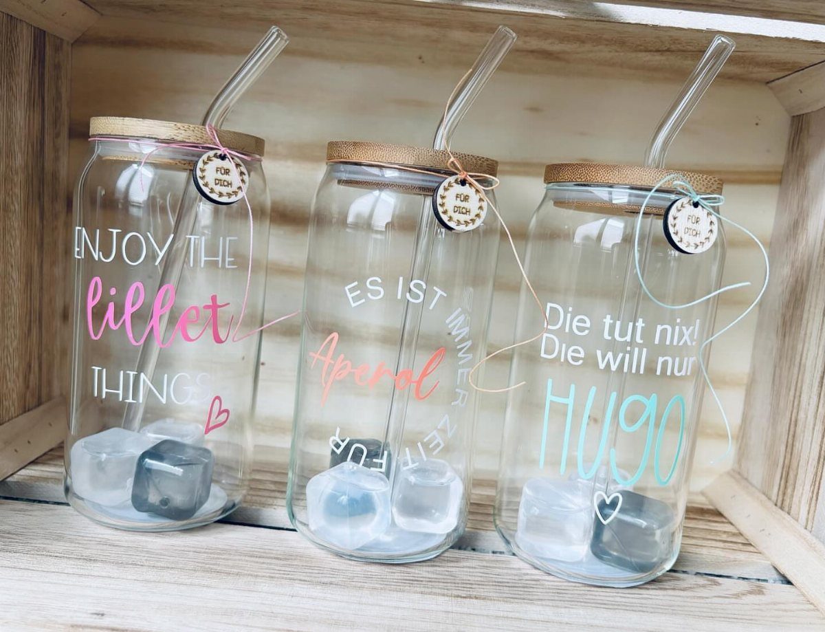 Three personalized glass mason jars with bamboo lids and glass straws in a crate.