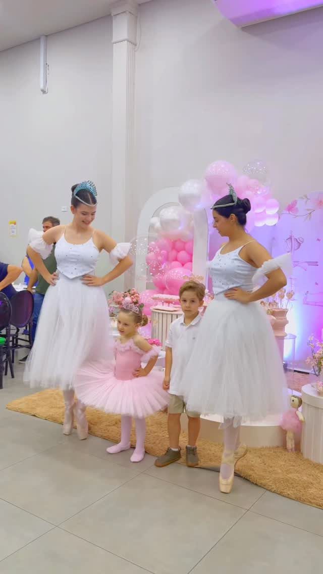 Ballerinas in white and pink tutus posing with children at a themed party