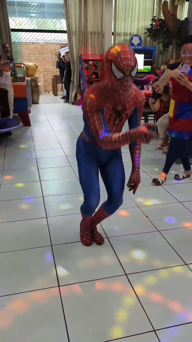 Person in Spider-Man costume dancing on a tiled floor with colorful disco lights.
