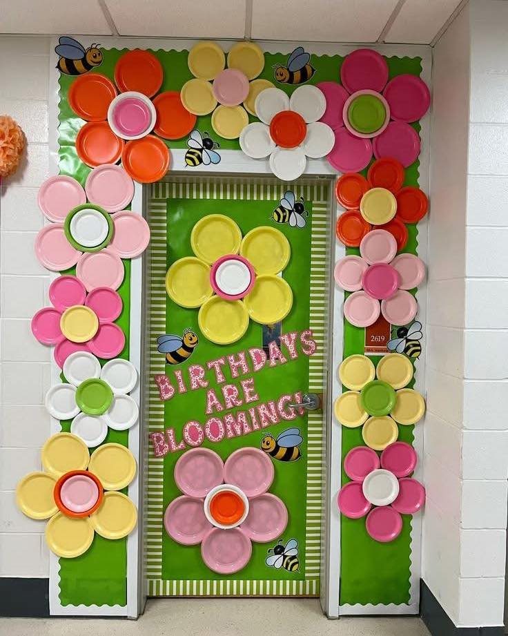 Classroom door decorated with colorful paper plate flowers and bees for birthdays.
