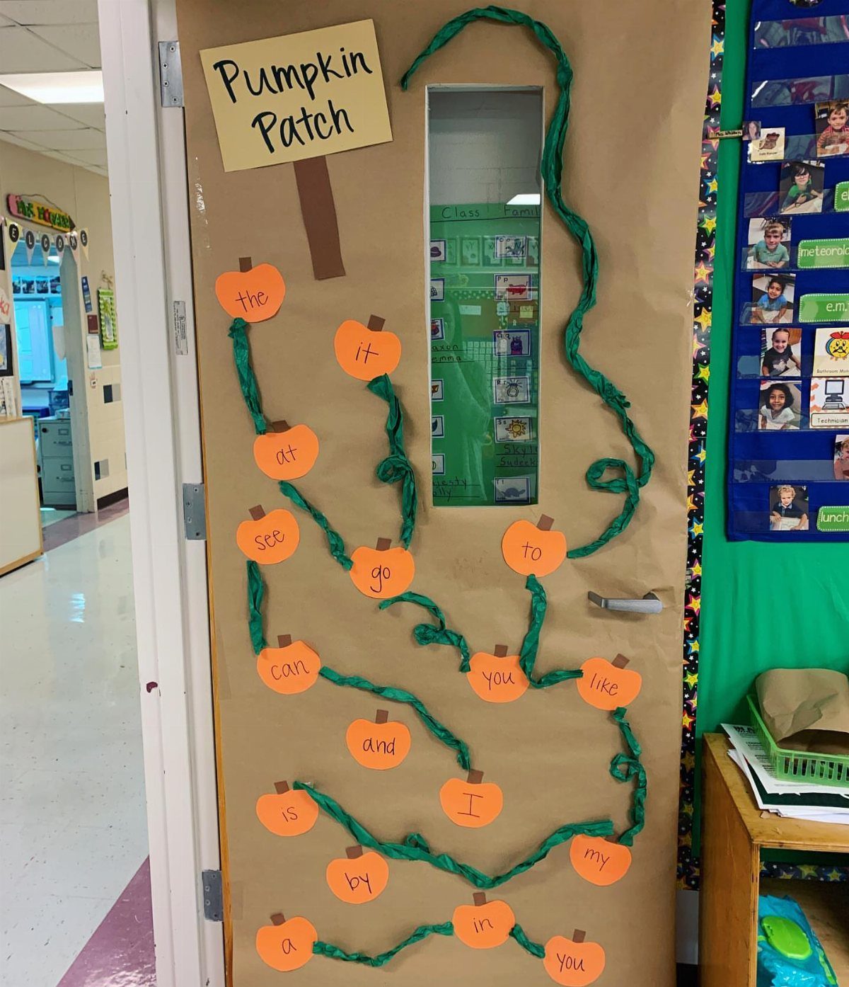 Classroom door decorated as a pumpkin patch with orange paper pumpkins and green vines.