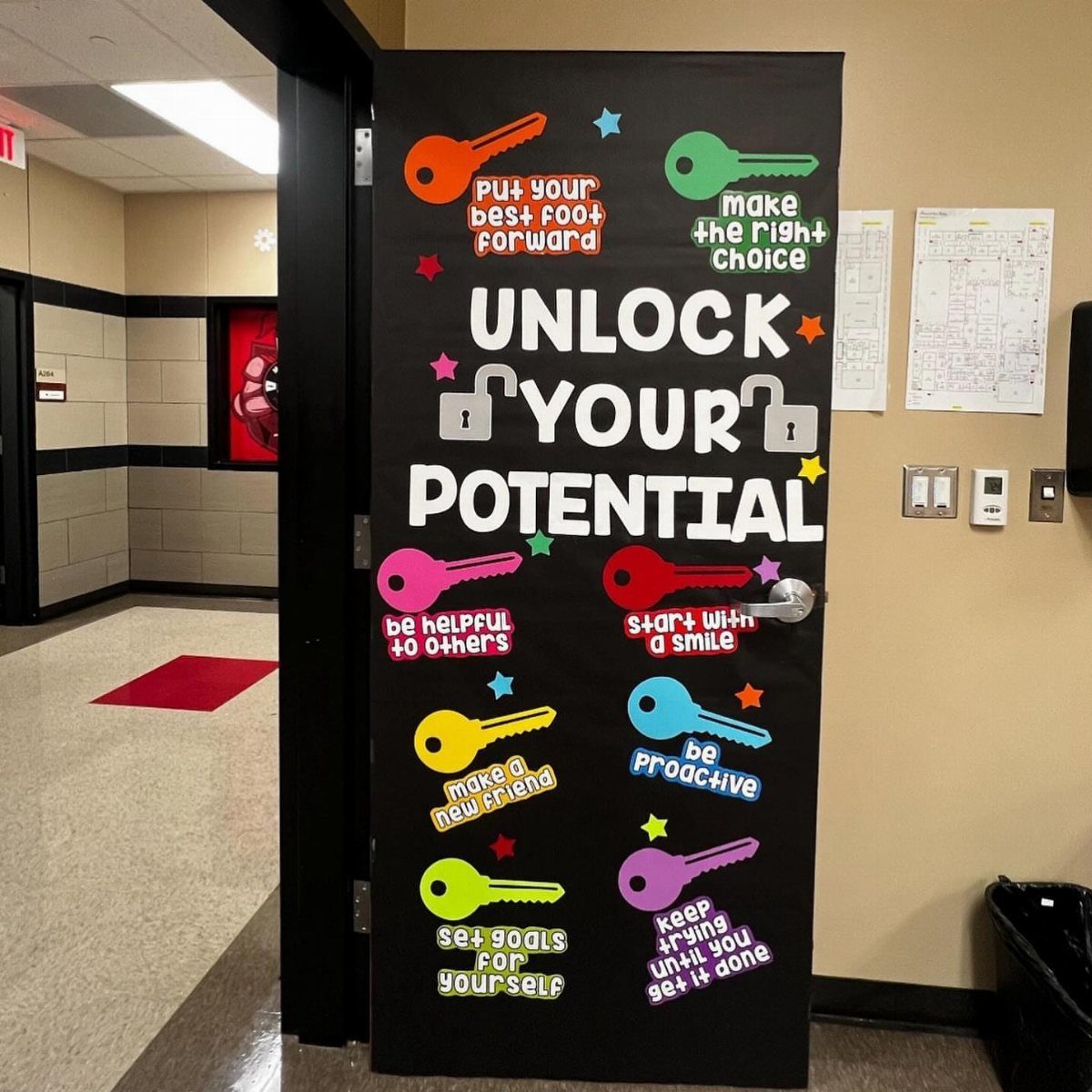 Black classroom door decorated with colorful paper keys and motivational growth mindset phrases.