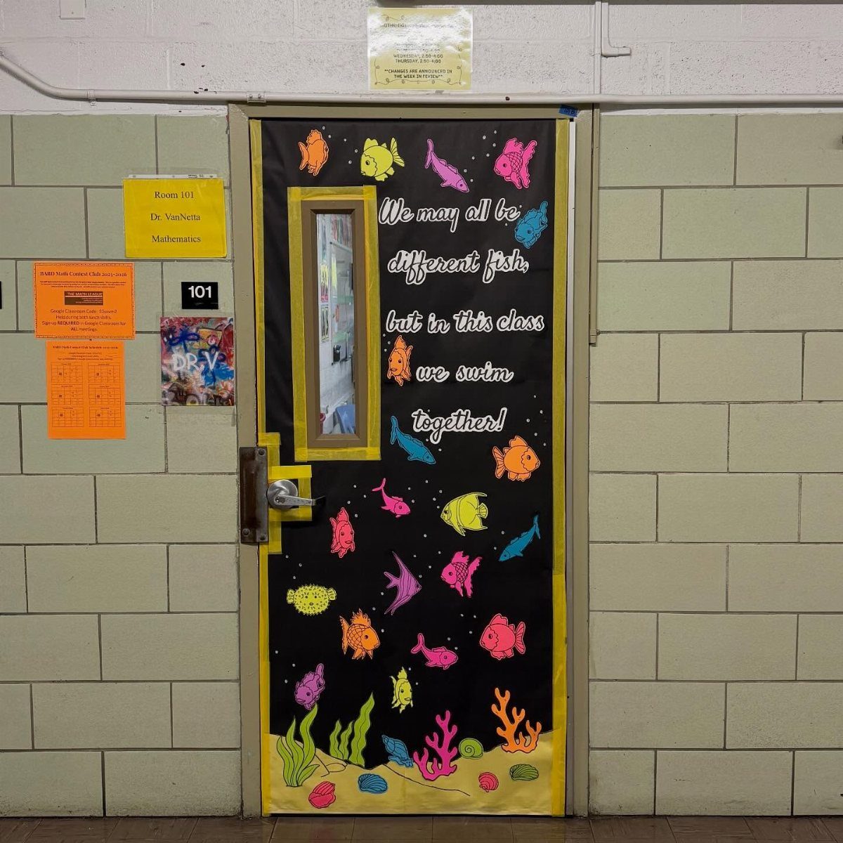 Ocean-themed classroom door with colorful neon fish and a motivational quote on black paper.