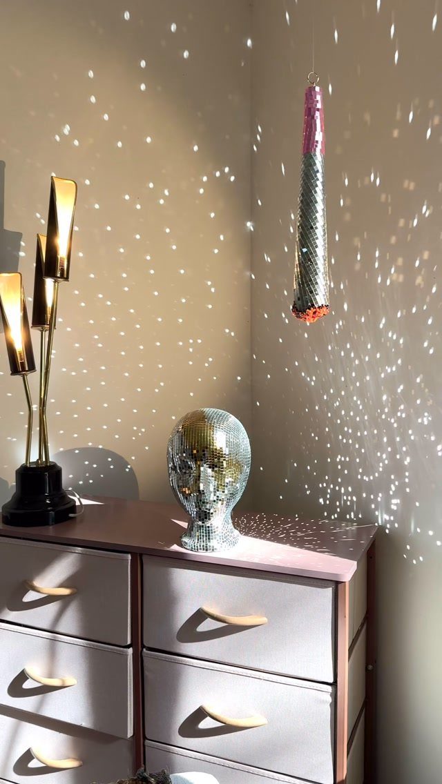 Mirrored disco ball head on a pink dresser with light speckles on walls