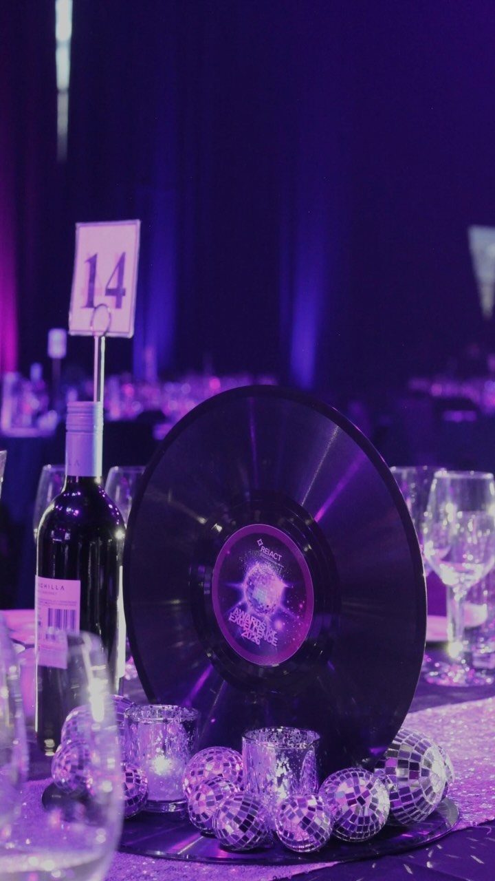 Vinyl record and small disco balls on a table with purple lighting.