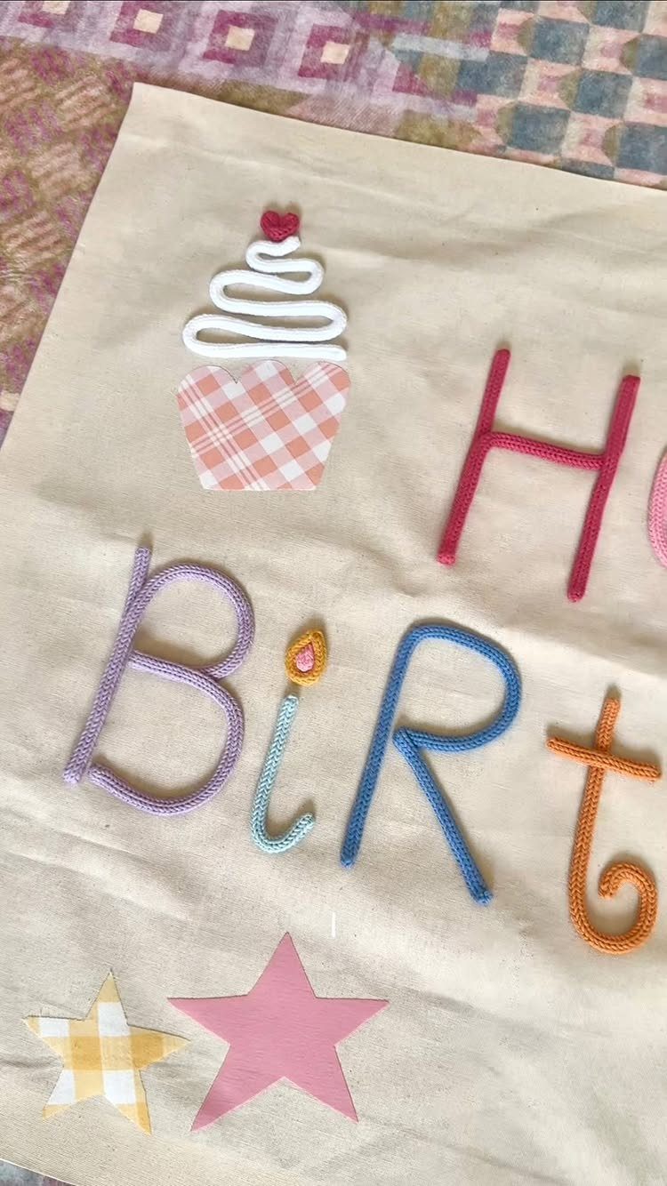Colorful pipe cleaner letters and shapes spelling birthday on beige fabric background