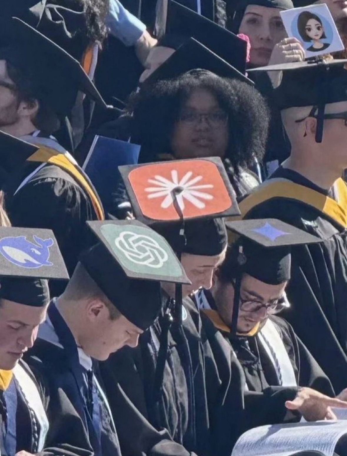 Graduates wearing black caps with custom decorated toppers featuring colorful graphic designs.